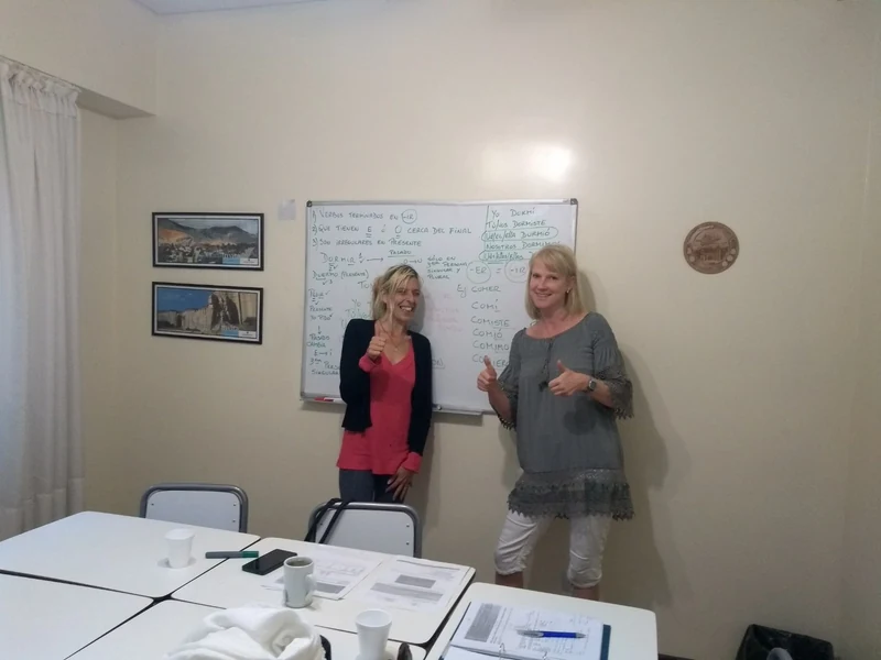A Verbum teacher and student working beside a whiteboard during a focused Spanish lesson